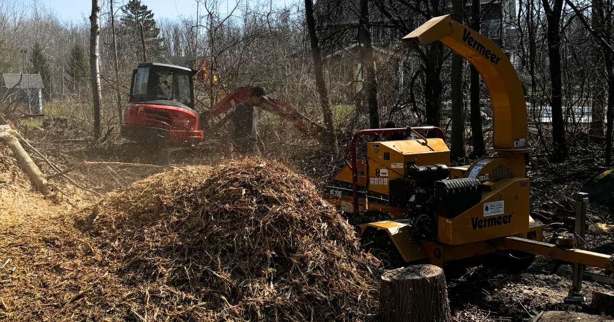 a wood chipper and a tractor breaking up trees