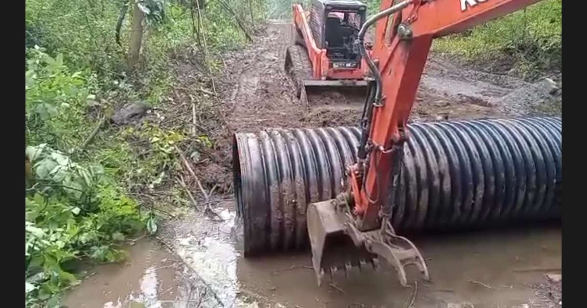 two machines laying a pipe under a road