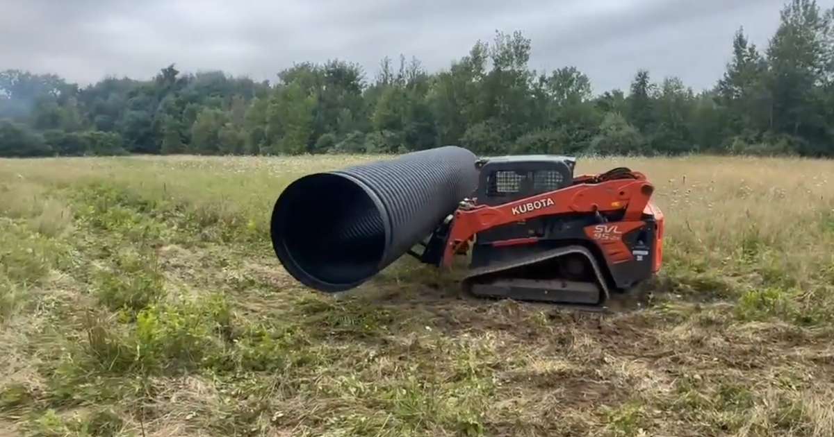 a tractor carrying a large pipe